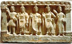 An early Mahayana Buddhist triad. From left to right, a Kushan devotee, the Bodhisattva Maitreya, the Buddha, the Bodhisattva Avalokitesvara, and a Buddhist monk. 2nd-3rd century, Gandhara.